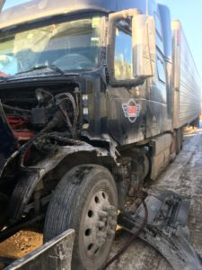 A black truck that has been hit by a train.