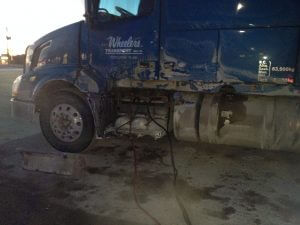 A blue truck with the front end of it's cab shattered.