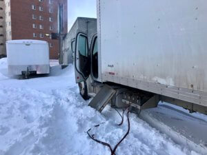 A truck is parked in the snow on the side of the road.