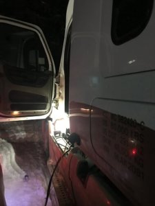 A truck with its door open and the lights on.