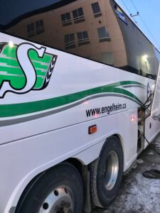 A white bus with green lettering on the side.