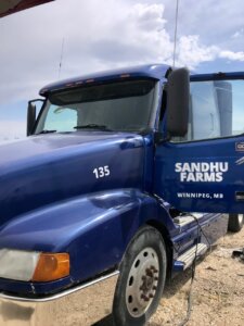 A blue truck parked on top of a dirt field.