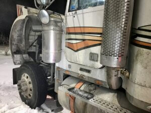A large truck parked in the snow with its front end exposed.