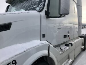 A white truck with its door open and the window broken.