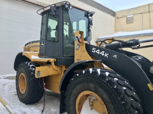 A yellow and black wheel loader parked in the snow.