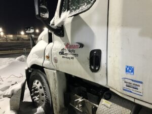 A white truck parked in the snow at night.